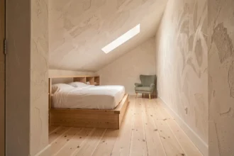Chambre étroite en longueur sous pente avec lit plateforme en chêne et étagères intégrées suivant la pente du toit